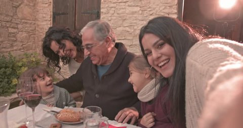 Family video-calling using smartphone during lunch at traditional village house in Italy