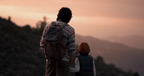 Young father and son hiking on mountain, standing on mountain peak and looking at view Stock Video