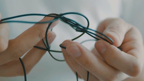 Man untangling tangled earbuds, Headphone wire tangled