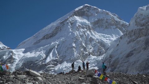 Tourists stand on the spot where the base camp of Everest is located. The mountain behind them is Mount Everest. The highest mountain in the world. 4K