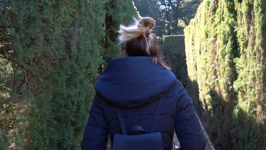 Woman walking through a hedge maze on a sunny winter day