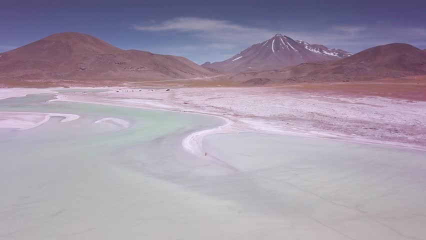 Aerial view of woman walking on the lakeside wearing a red dress, Altiplanic lagoons in the Atacama Desert, Chile, 4k