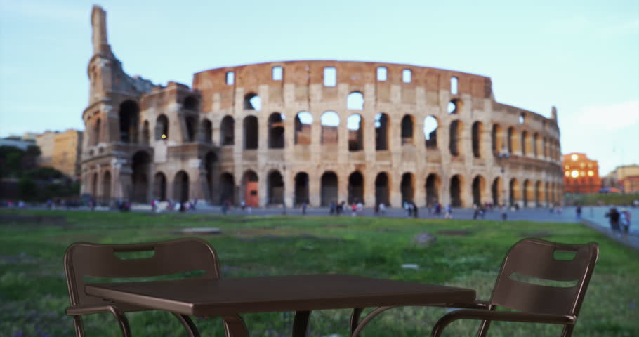 2 young attractive women getting together at table to look at smartphone near Colosseum in Rome, Italy. Couple of pretty ladies in summer dresses being social in Italy. 4k