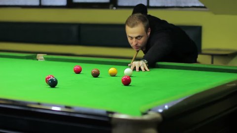 Young player playing billiards. A snooker player hitting the ball