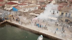 Aerial drone bird's eye view video of people participating in traditional colourful flour war or Alevromoutzouromata part of Carnival festivities in historic port of Galaxidi, Fokida, Greece