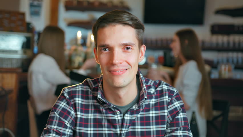Happy young man smiling and looking in camera in restaurant