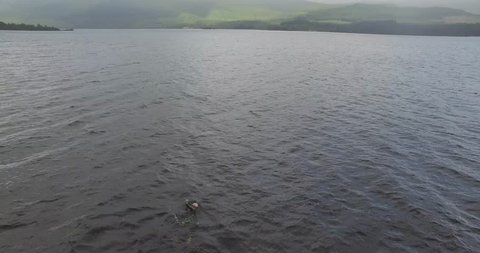 Aerial of male triathlete swimming across a lake in Scotland