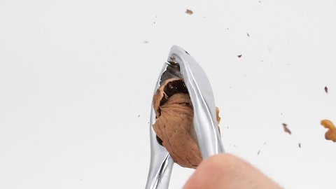 Broken walnut with nutcracker on a white background, slow-motion