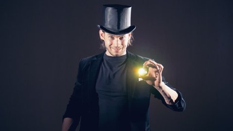 Magician is making a sparkling crystal disappear from his right fist and taking from the air.