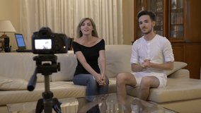 Attractive young couple of vloggers recording a new video tutorial to promote on social media at home on couch