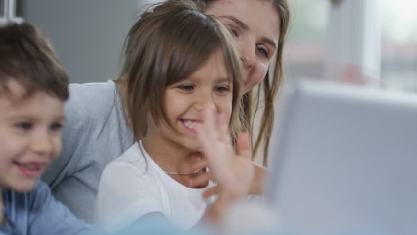 Mother and two preschool children using laptop computer for online communication, laughing and greeting someone they see on the screen Royalty-Free Stock Footage #1007755390