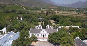 4K summer day aerial video view of Western Cape's Stellenbosch wine estates area, Lanzerac's beautiful hilly garden and twin peaks view, grape plantations in background near Cape Town, South Africa