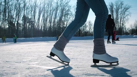Young woman skating on ice with figure skates outdoors in the snow. Close-up Stockvideó
