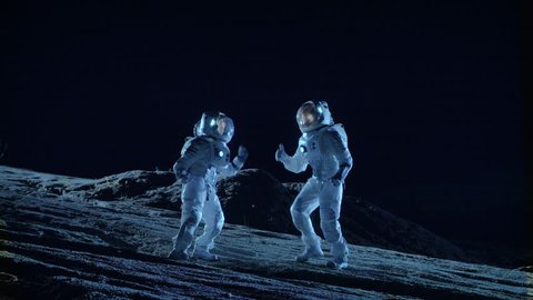 Male and Female Astronauts Wearing Space Suits Dance on the Surface of the Alien Planet. Humanity Colonizing Space Celebration Theme. Shot on RED EPIC-W 8K Helium Cinema Camera.