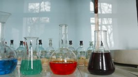 Panoramic video of chemical glass flasks and test bottles with colored liquids on the table in laboratory
