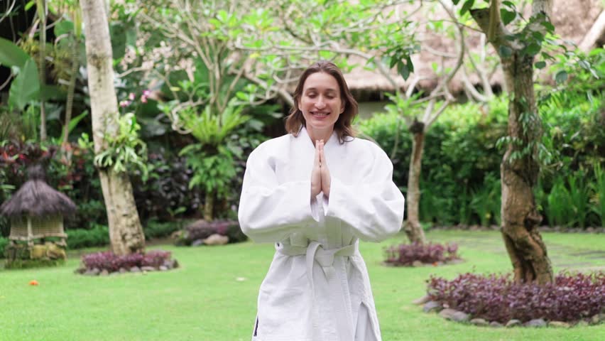 Young woman practicing aikido with ethnic master in green garden.