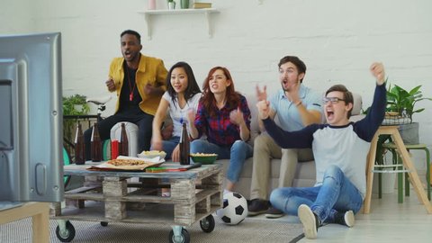 Group of happy friends watching sports game on TV at home. They are happy about their favorite team win competition Video Stok