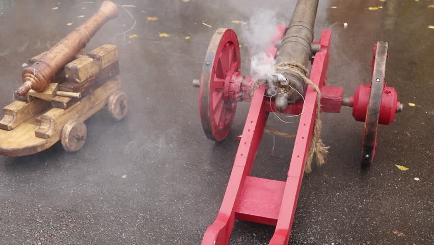Old cast-iron cannon on wooden carriage smokes shoots, slow motion