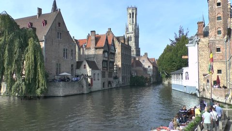Belgium, Bruges. 09/25/2017. Landscape with a bell tower and boats in the canal.