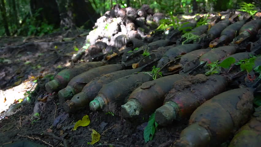 A medium shot of old grenades on ground. Camera pans to the right