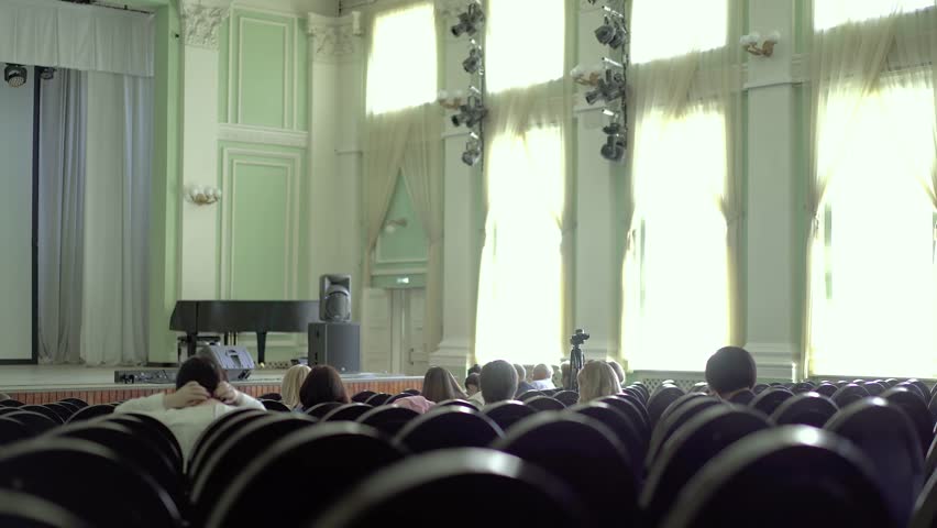 People are sitting in the concert hall, waiting for the beginning of the performance. 