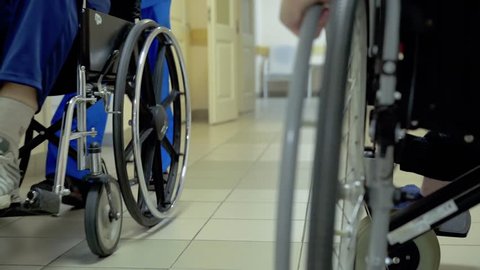 Young guy, a disabled person with a lesion of the spinal cord and legs, multiple sclerosis, moves through the hospital corridor in a wheelchair. 