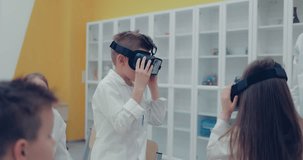 Schoolgirl and schoolboy in the classroom watching in virtual reality glasses