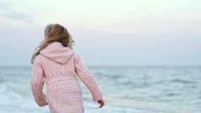 Full length view of Pretty little girl in warm clothes running on beach
