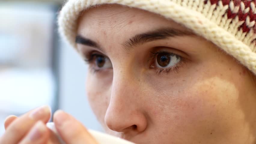 A young woman drinks coffee and listens to her interlocutor.