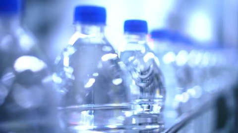 Clean water in plastic bottle moves through conveyor factory.