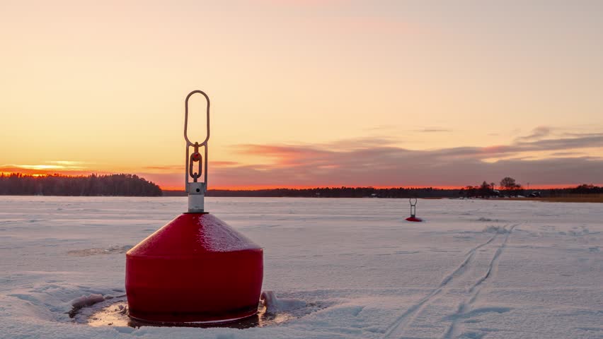 Frozen buoy against the backdrop of a beautiful sunset. Time lapse.