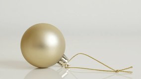 Golden bauble on white slow tilt 4K 2160p 30fps UltraHD footage - Shiny Christmas ornament in gold color close-up 3840X2160 UHD video