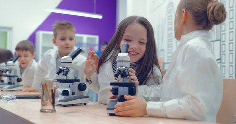 Boys and girls looking through microscope in laboratory at school