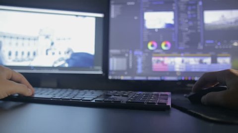 Video editing process in timelapse, table with 2 monitors and black keyboard in dark room