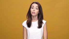 Young displeased emotional woman standing isolated over yellow background while looking camera showing crazy gesture