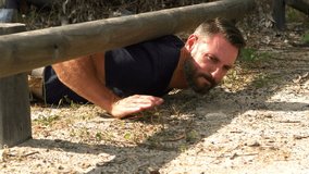 Man crawling under the hurdle during obstacle course in the bootcamp - Powered by Shutterstock - Get 15% off with code: PIKWIZARD15