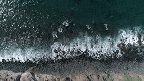 Aerial - Top down view of long waves crushing against the coast line on Tenerife