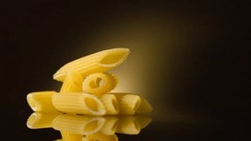 Pasta Penne rotated on dark background. Italian mediterranean food, diet, dieting. Cooking Italian pasta penne close-up. Slow motion 4K UHD video