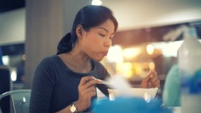 Young Asian Lady eating noodle soup in food court toned video 4k UHD (3840x2160)