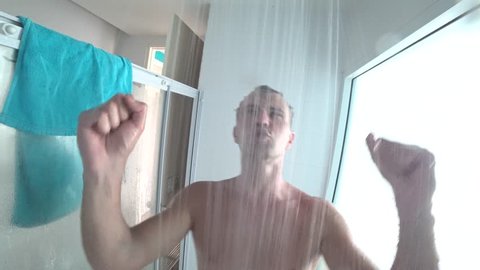 young handsome muscular man takes a shower. the guy washes, sings and dances in the shower. action camera. 