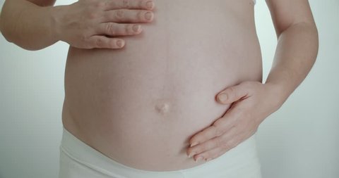 pregnant girl stroking her belly hands while wiggling baby