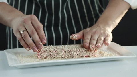 The chef sprinkles sesame seeds on the tuna fillet