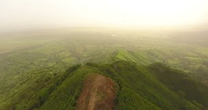 Aerial drone bird's eye view video on a beautiful mountain covered with green grass. On top of the mountain there is a farm. tropical paradise pacific atoll islands. Top view. Shot in 4k