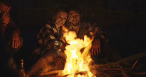 Couple enjoying with friends and drinking beer at night at beach