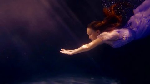 a young girl in a gorgeous dress swims by the water, on top of her light falls