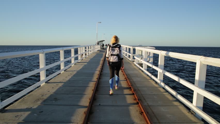 Carefree young sporty woman at Busselton jetty in Busselton, Western Australia. Happy female over iconic wooden pier in WA. Australia travel and freedom concept.