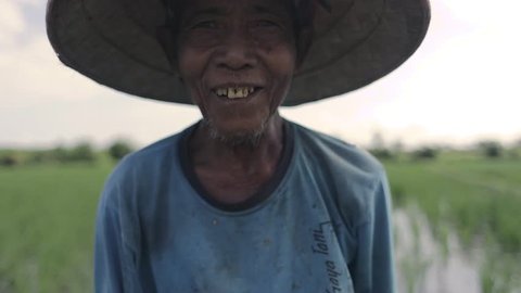 UBUD, BALI INDONESIA / AUGUST 28, 2017 BalInese farmer working on the rice fields smiling at the camera in Bali Indonesia