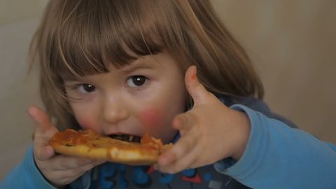 Cute little Caucasian boy eating pizza. Hungry child taking a bite from pizza.  