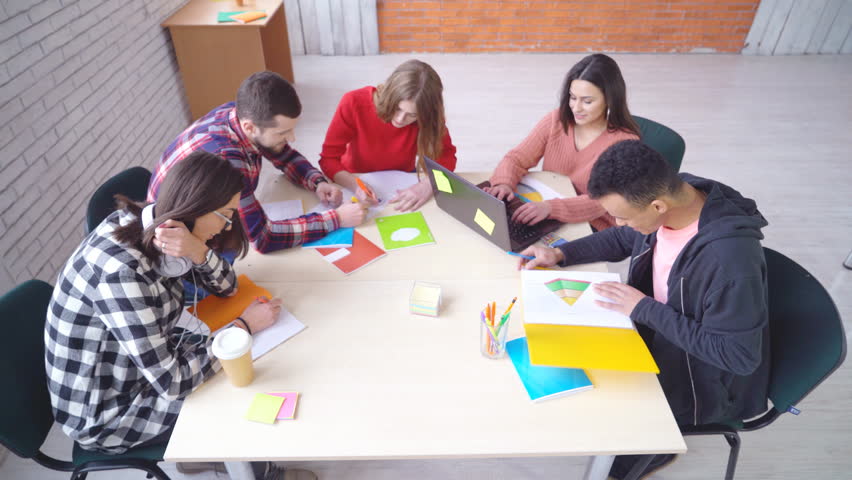 a group of young attractive people mixed race students engaged in the office at the table. shooting view up. people sit down and stand up at the table in turn. Royalty-Free Stock Footage #1007896522