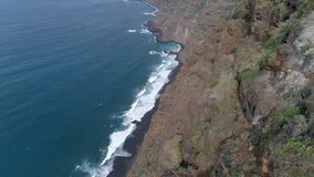Aerial - Flying above the cliff next the seaside. High angle view of ocean waves crushing against the coast line